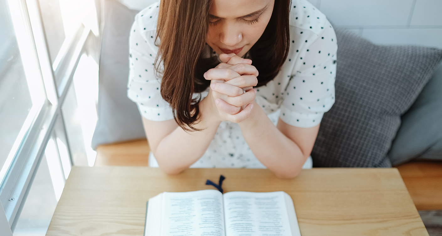 Asian woman praying with bible