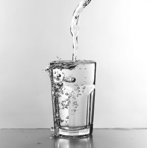 water pouring and overflowing into a clean cup